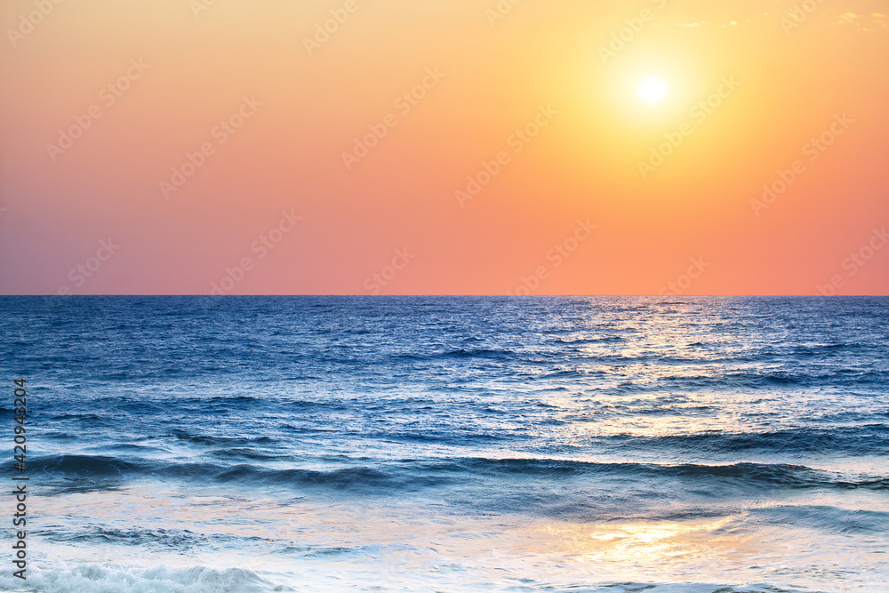 Beautiful sunset landscape, blue sea, ocean waves, tropical island beach, red orange sky, yellow sun glow, reflection on water, purple clouds, morning sunrise, peaceful dawn, seascape scenery, nature
