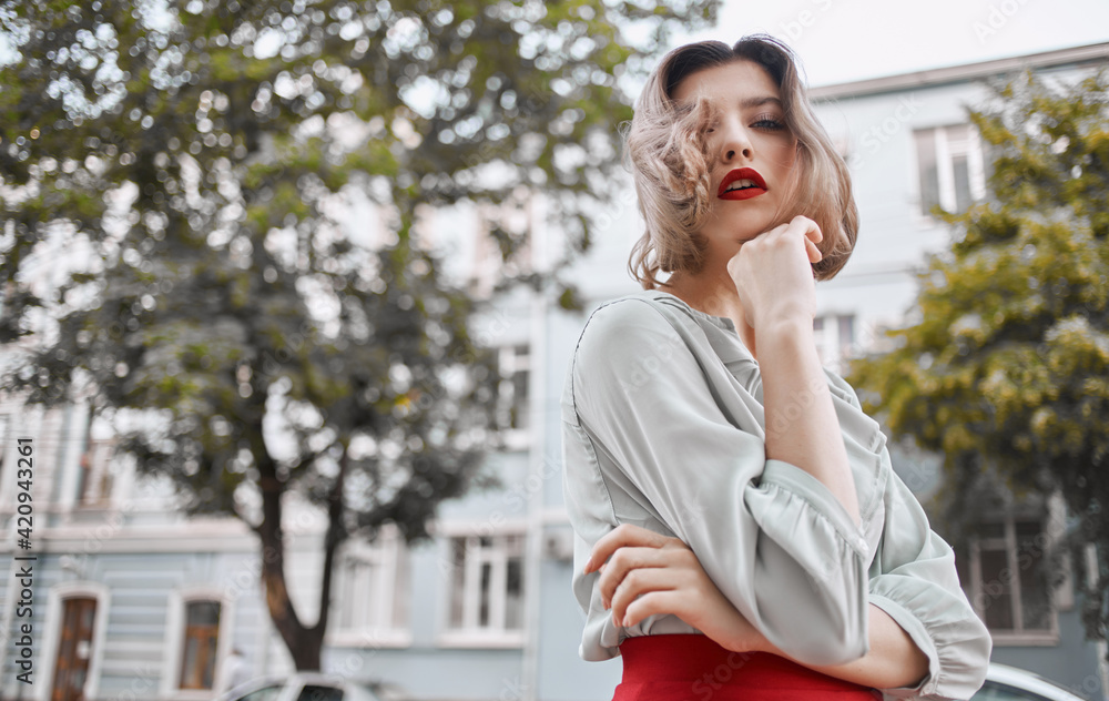 beautiful blonde with red lips outdoors near the building gestures with her hands emotions Copy Space