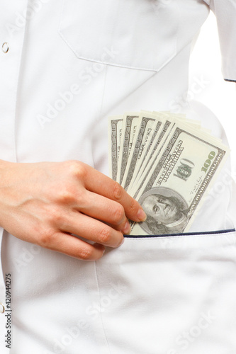 Woman doctor with stethoscope and currencies dollar in apron pocket
