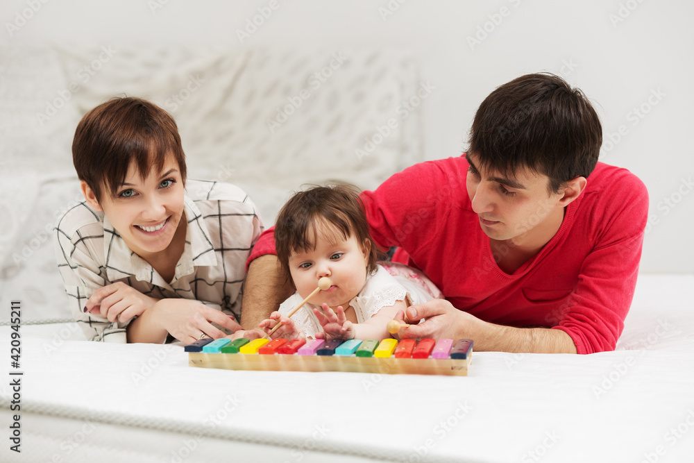 Happy young family with baby girl playing xylophone toy Happy young family with baby girl playing xylophone toy