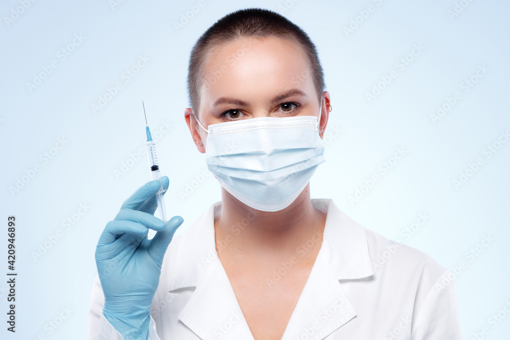 Short-haired woman doctor in mask holding syringe with medication Short-haired woman doctor in mask holding syringe with medication