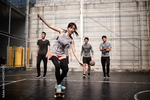 young asian female skateboarder and her male friends