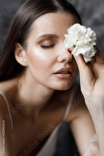 Portrait of a young attractive bride with a flower on her face. A modern European-style wedding in the studio.