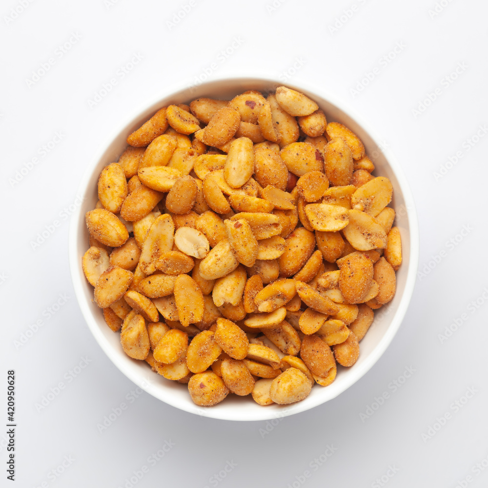 Close up of Crunchy masala peanuts Indian namkeen (snacks) on a ceramic white bowl. Top view Close up of Crunchy masala peanuts Indian namkeen (snacks) on a ceramic white bowl. Top view