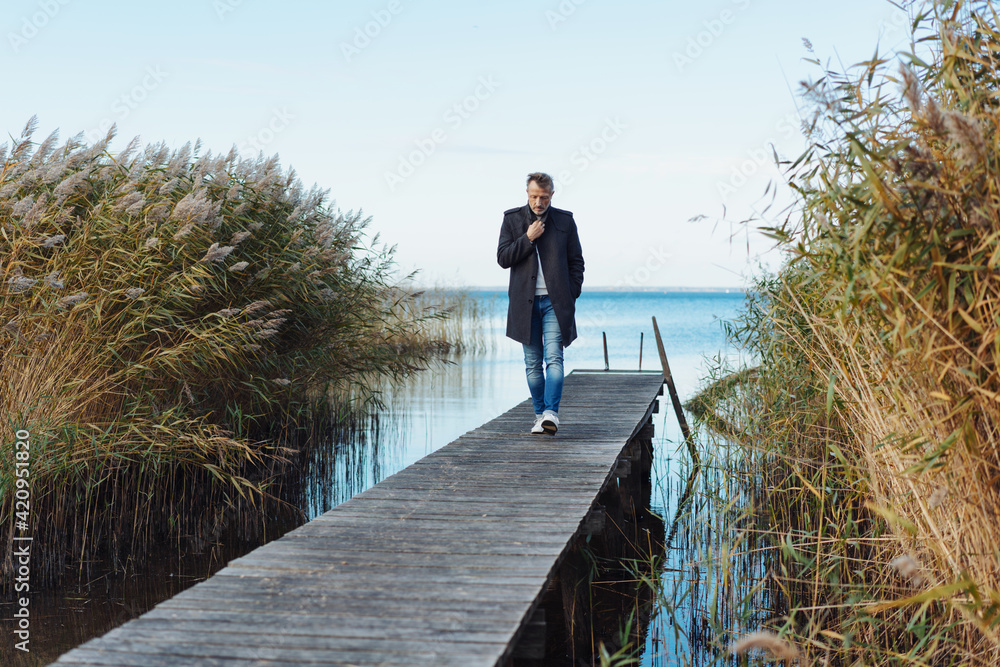 Lonely man walking on a wooden jetty on a cold winter day