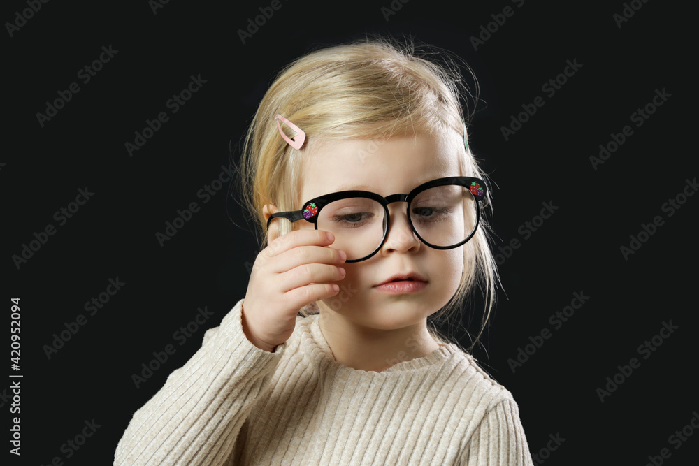 Studio portrait of adorable little toddler girl wearing reading glasses