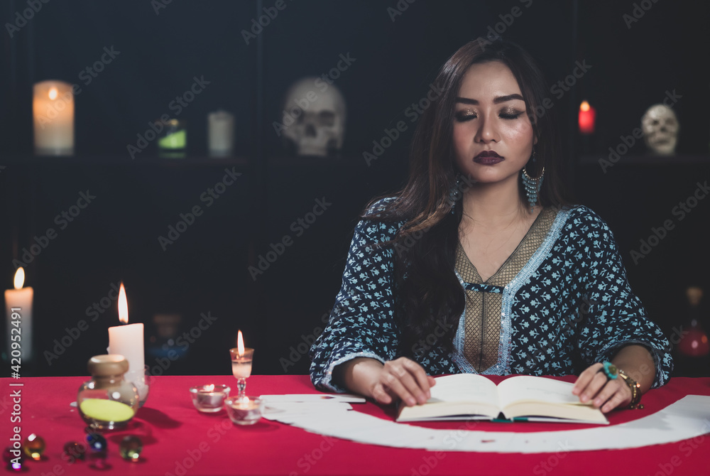 Asian sorceress reading fortune in book Asian sorceress reading fortune in book