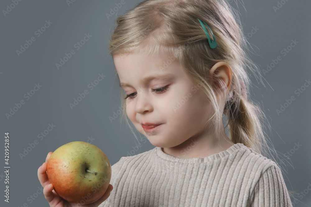 Studio portrait of adorable little toddler girl eating apple Studio portrait of adorable little toddler girl eating apple