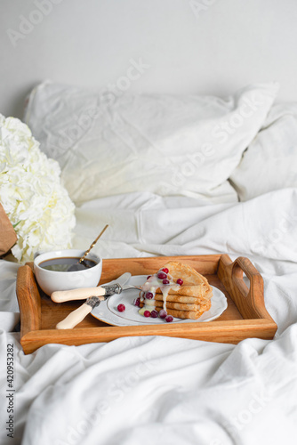 Food tray. Thin pancakes with condensed milk and berries. Romantic breakfast with pancakes and coffee and flowers in bed. Copy space