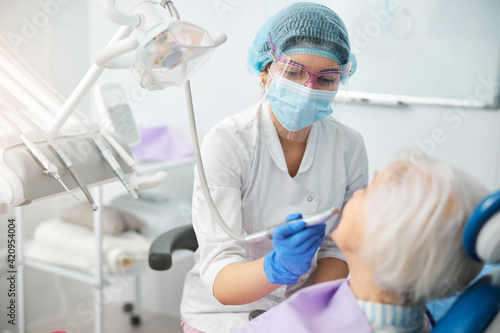 Doctor performing tooth polishing on senior person