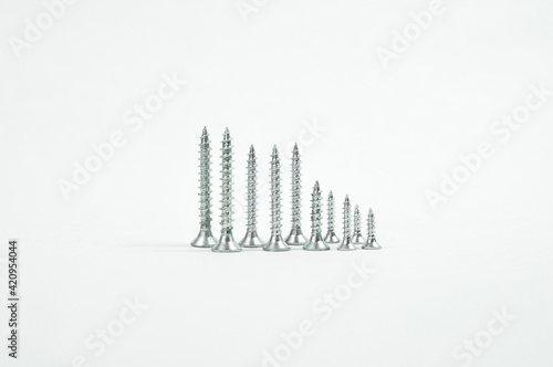 metal self-tapping screws of different diameters and different heights stand point up on a white background