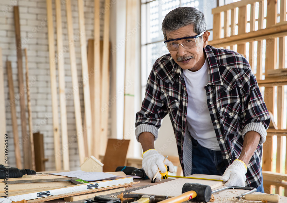 Senior Asian joiner measuring plank Senior Asian joiner measuring plank