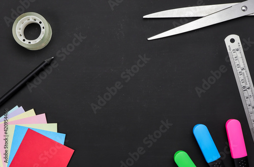 School supplies on black board background.Top view with copy space. Back to school concept.