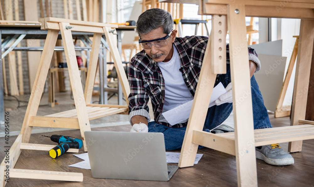 Asian artisan with laptop making lumber furniture Asian artisan with laptop making lumber furniture