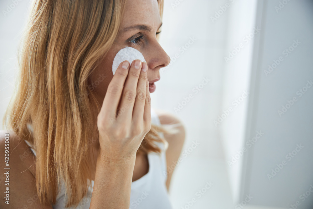 Beautiful woman cleaning skin with cotton pad at home Beautiful woman cleaning skin with cotton pad at home
