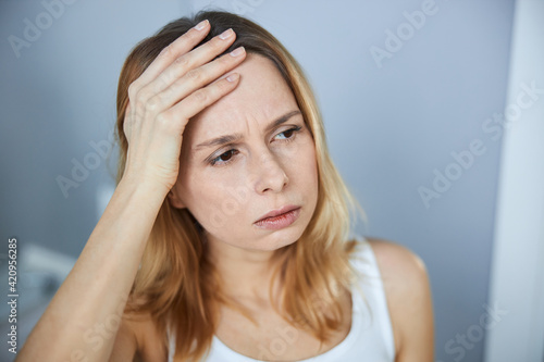 Unhappy young woman having headache at home
