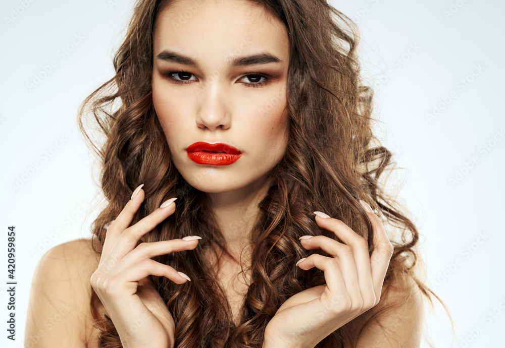 Beautiful brunette woman with bright makeup touches curly hair on her head with her hands Beautiful brunette woman with bright makeup touches curly hair on her head with her hands
