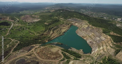 Inoperative blue water flooded quarry with big dumps. Mining industry in Ural Mountains. Aerial drone wide view at summer sunny day photo