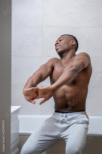 African american sporty guy looking sleepy and stretching