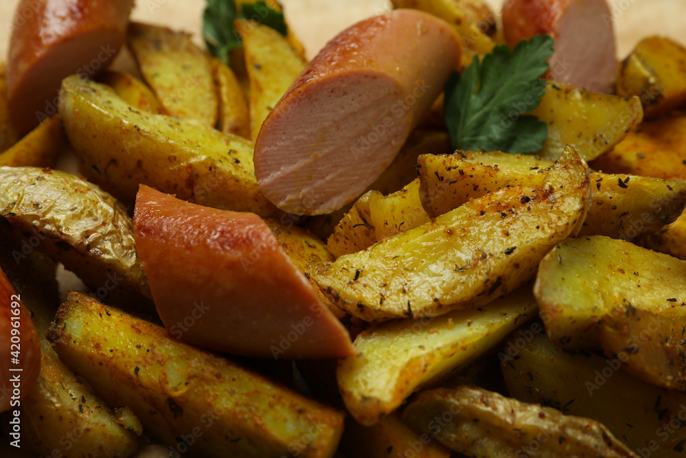 Potato wedges with spices and fried sausage, close up Potato wedges with spices and fried sausage, close up