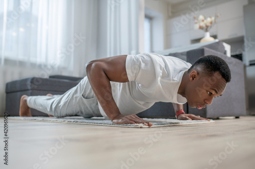 African american guy in white clothes doing morning exercises