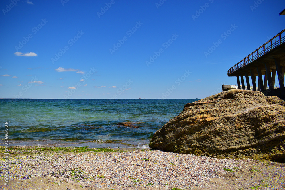 A picturesque seascape overlooking the blue sea, rocks and stones on a bright sunny day. on the beach. Wonderful view on the coast. Bright sun, blue sea. Vivid summer ambience, vacation, tourism