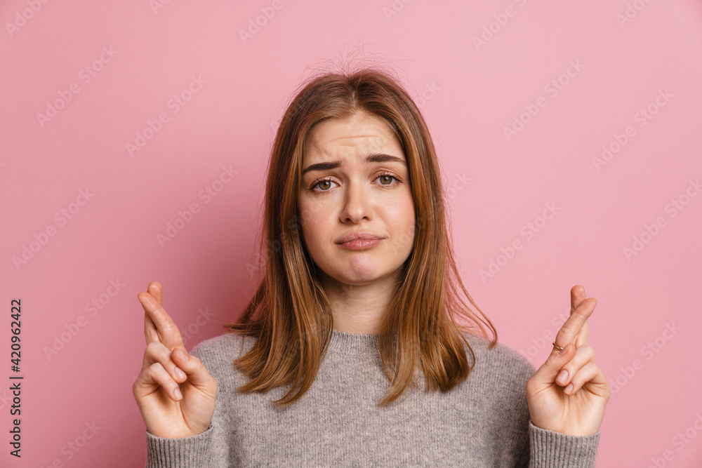 Ginger upset woman posing with fingers crossed for good luck Ginger upset woman posing with fingers crossed for good luck