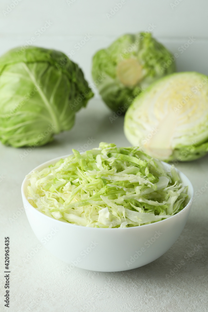 Bowl with sliced cabbage and fresh cabbage on white textured table Bowl with sliced cabbage and fresh cabbage on white textured table