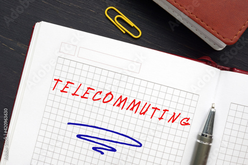 Business concept about TELECOMMUTING with inscription on the page. Telecommuting is an employment arrangement in which the employee works outside of the employer's office.