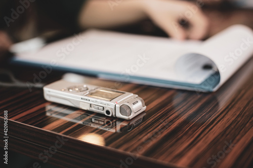 Shallow depth of field (selective focus) image with an audio recorder of a woman journalist during an interview.