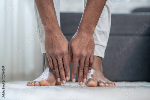 Close up picture of dark-skinned mans hands touching the floor