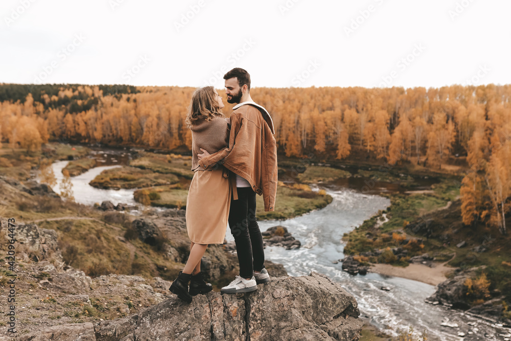 Happy in love romantic young cheerful couple man and woman married travel hiking walk together among the autumn forest and mountains looking for adventure enjoy the local nature, selective focus Happy in love romantic young cheerful couple man and woman married travel hiking walk together among the autumn forest and mountains looking for adventure enjoy the local nature, selective focus