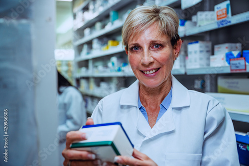 Caucasian female pharmacist looking at labels of prescription medication standing in pharmacy 