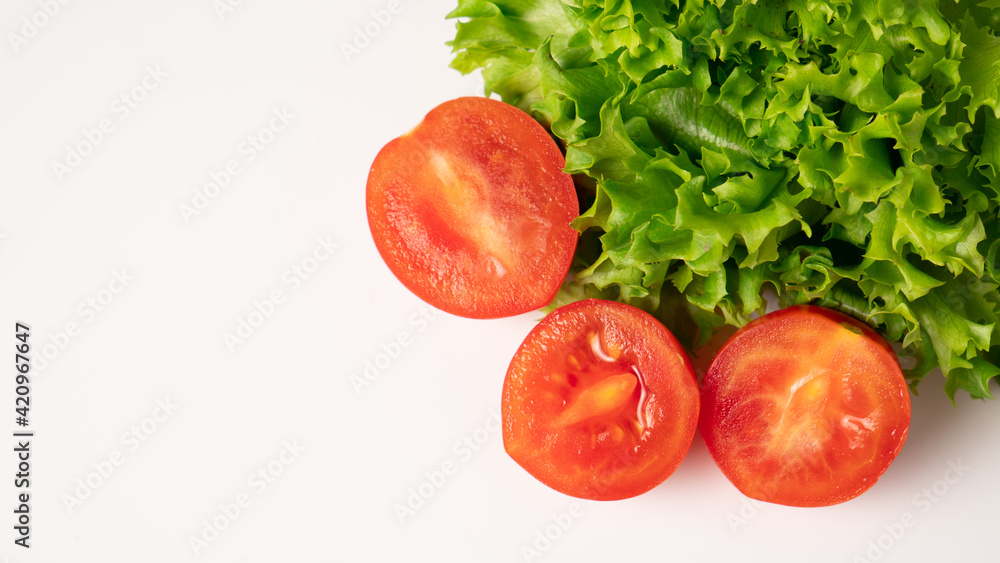 Three juicy sliced cherry tomatoes in the right corner with green lettuce on a white background. Isolated. Copy space Three juicy sliced cherry tomatoes in the right corner with green lettuce on a white background. Isolated. Copy space