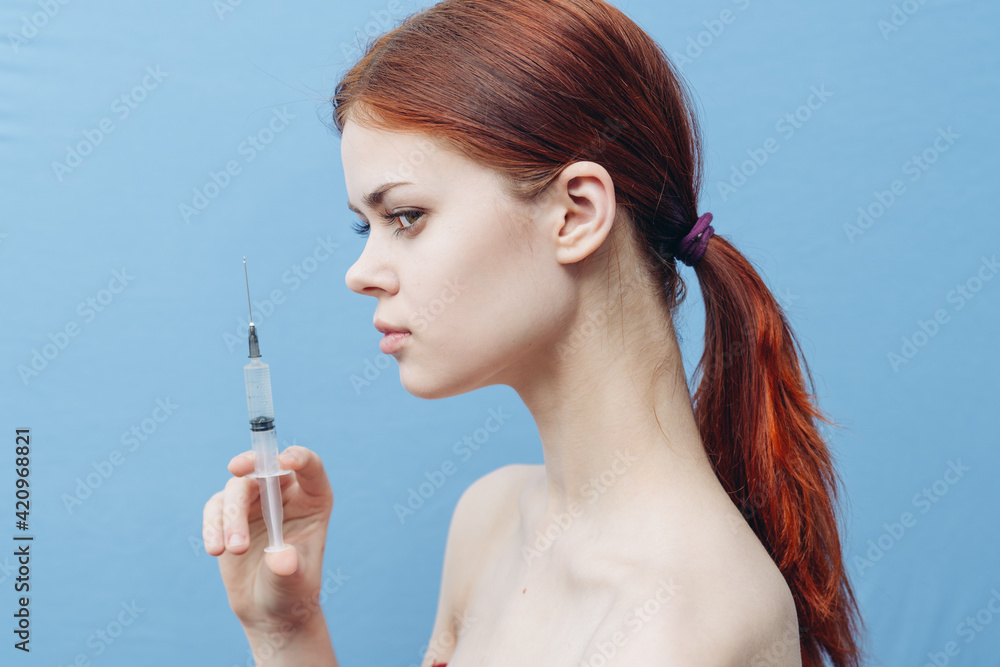 Obraz premium women make injections for rejuvenation on a blue background And syringe in hand side view