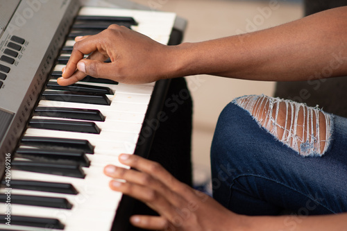 a young black lady playing a piano, hands only