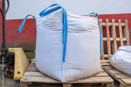 Fotografie Stack of raffia large sand sack over Hand Pallet Jack Hydraulic Welding Pump
