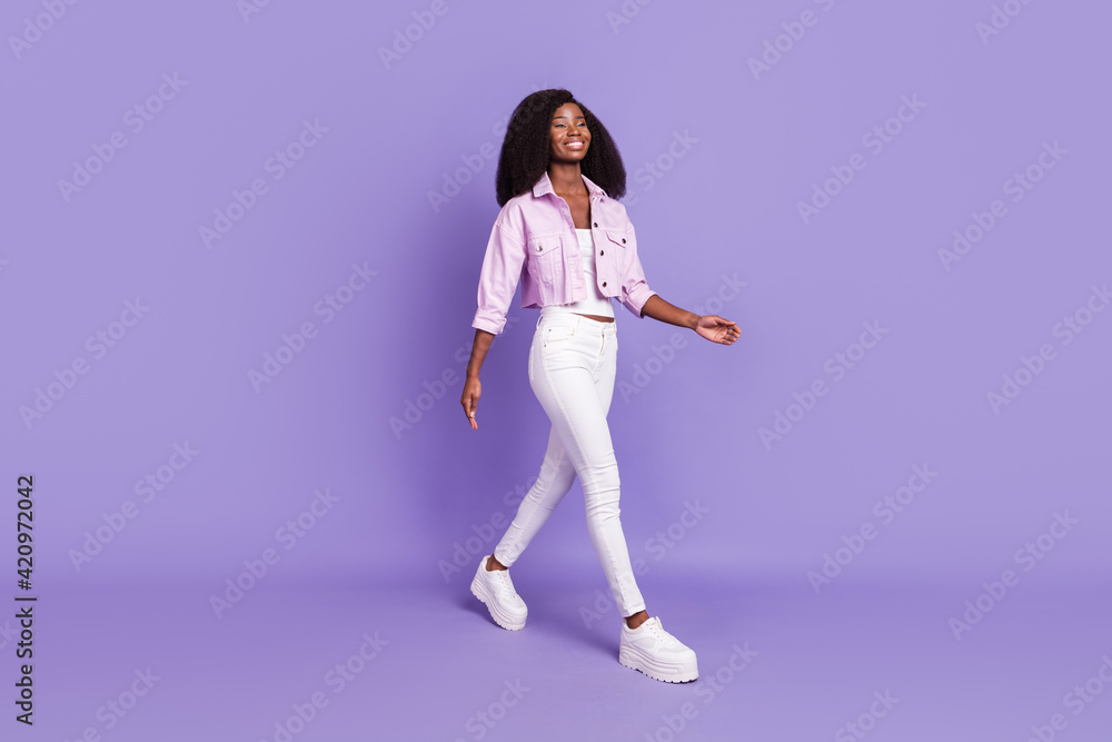 Full size photo of young beautiful smiling positive afro girl go walk looking copyspace isolated on violet color background Full size photo of young beautiful smiling positive afro girl go walk looking copyspace isolated on violet color background