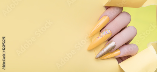 Photo Female hand with yellow nail design