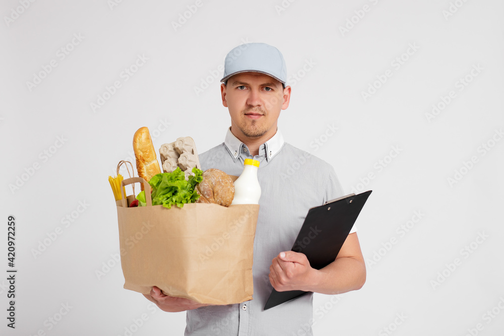 food delivery concept - delivery man in uniform with paper bag full of products over white background