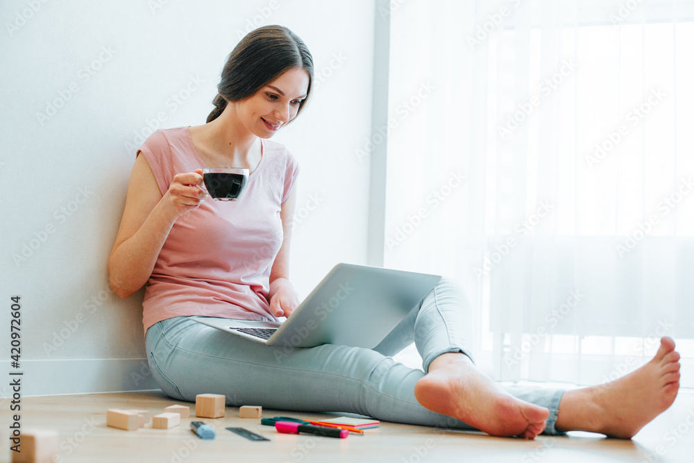 Obraz premium Contented smiling young female working on the laptop