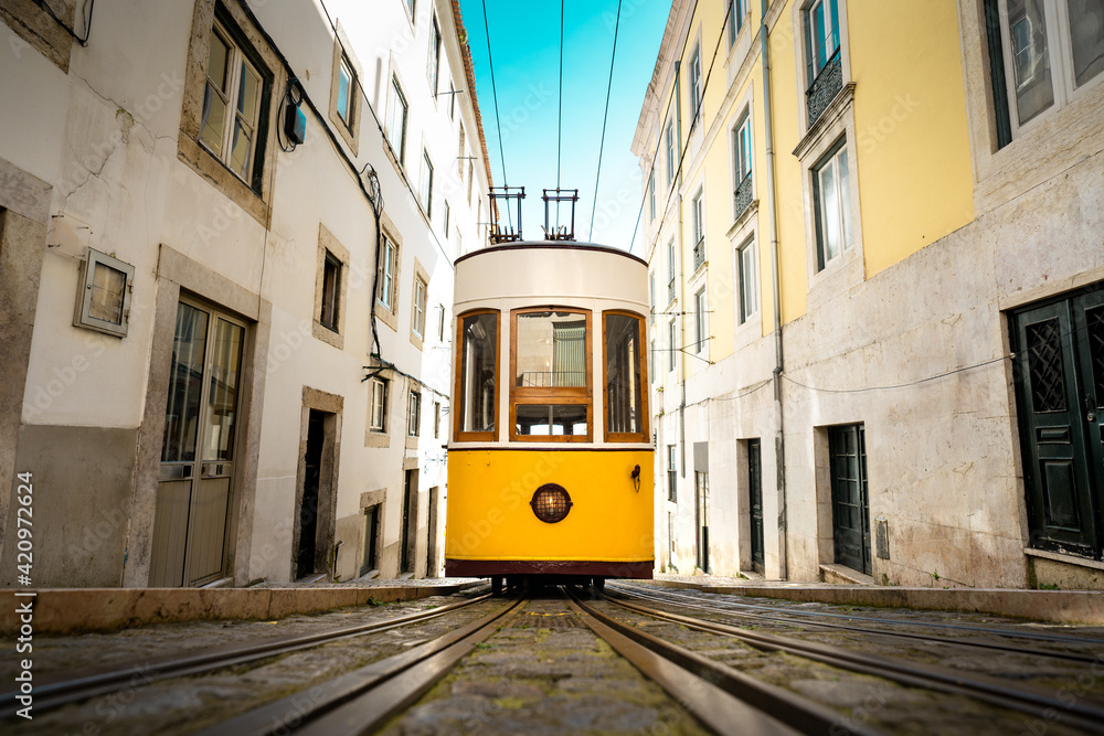 Trams in Lisbon. Famous retro yellow funicular tram on narrow streets of Lisbon. Tourist sightseeing or tourist attraction in Lisbon, Portugal