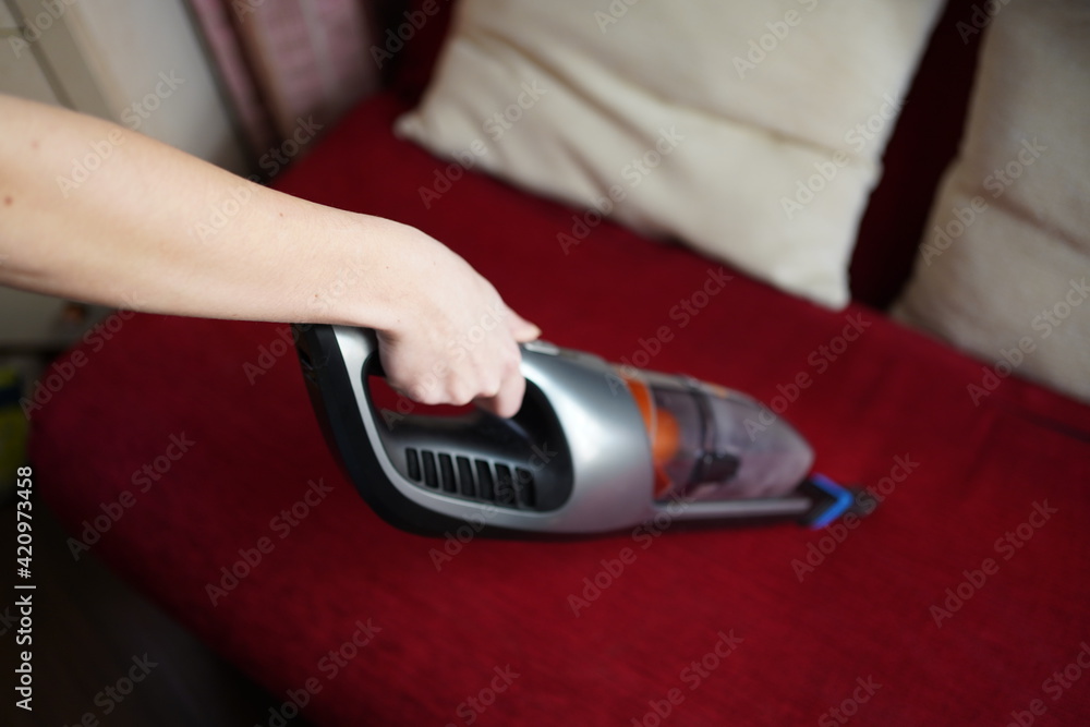 Fototapeta premium Cleaning with a portable cordless vacuum cleaner. Soft selective focus
