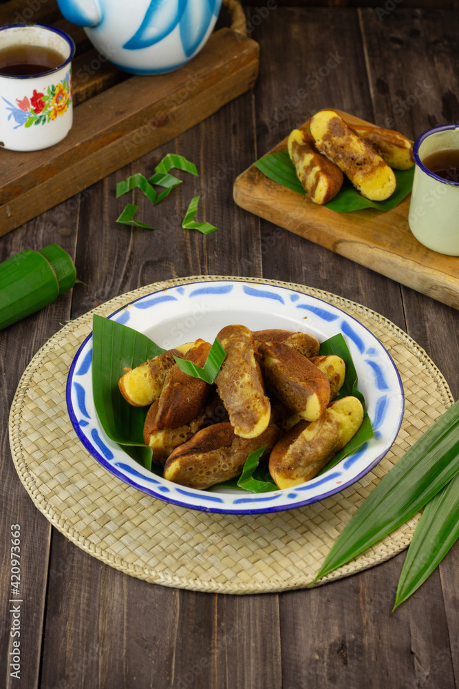 Kue Pukis, Indonesian popular traditional sweet cake, made from flour, eggs, sugar, milk or coconut milk, served on enamel plate,  usually at tea time or snack time.  Dark wooden background.