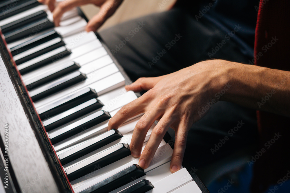 Top view of unrecognizable musician man playing on synthesize at home studio. Close-up hands of pianist male playing on digital piano in living room. Concept of music education. Top view of unrecognizable musician man playing on synthesize at home studio. Close-up hands of pianist male playing on digital piano in living room. Concept of music education.