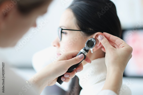 Foto Otorhinolaryngologist examines patient ear with an otoscope