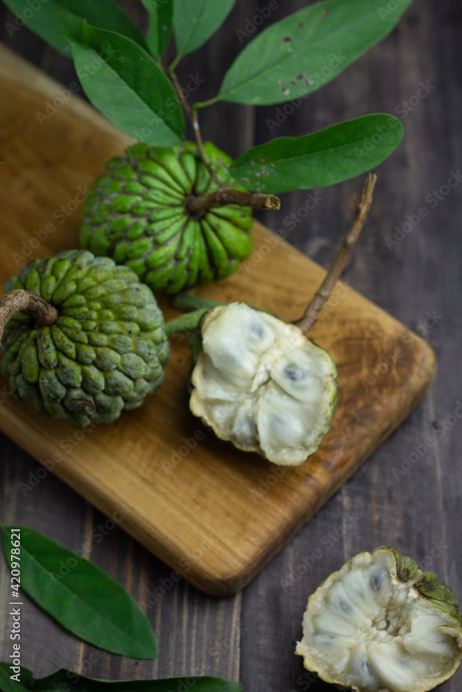 Buah Srikaya or sugar apple or annona squamosa, one of Indonesian tropical fruits. Sweet taste and green skin fruit. Dark wooden background, copy space for text.