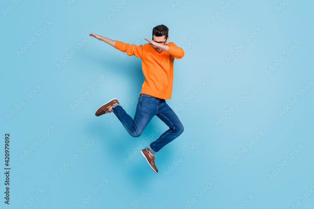 Full length photo of young excited man jump up dab hip-hop dance active energetic isolated over blue color background