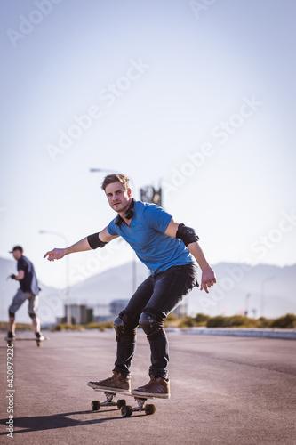Fototapeta Naklejka Na Ścianę i Meble -  Skateboarder skateboarding on an open road doing freestyle tricks