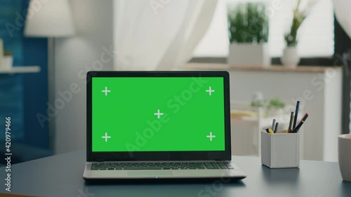 Laptop computer with mock up green screen chroma key standing on home office desk with nobody in it. Professional set up is ready for e commmerce courses using isolated pc photo